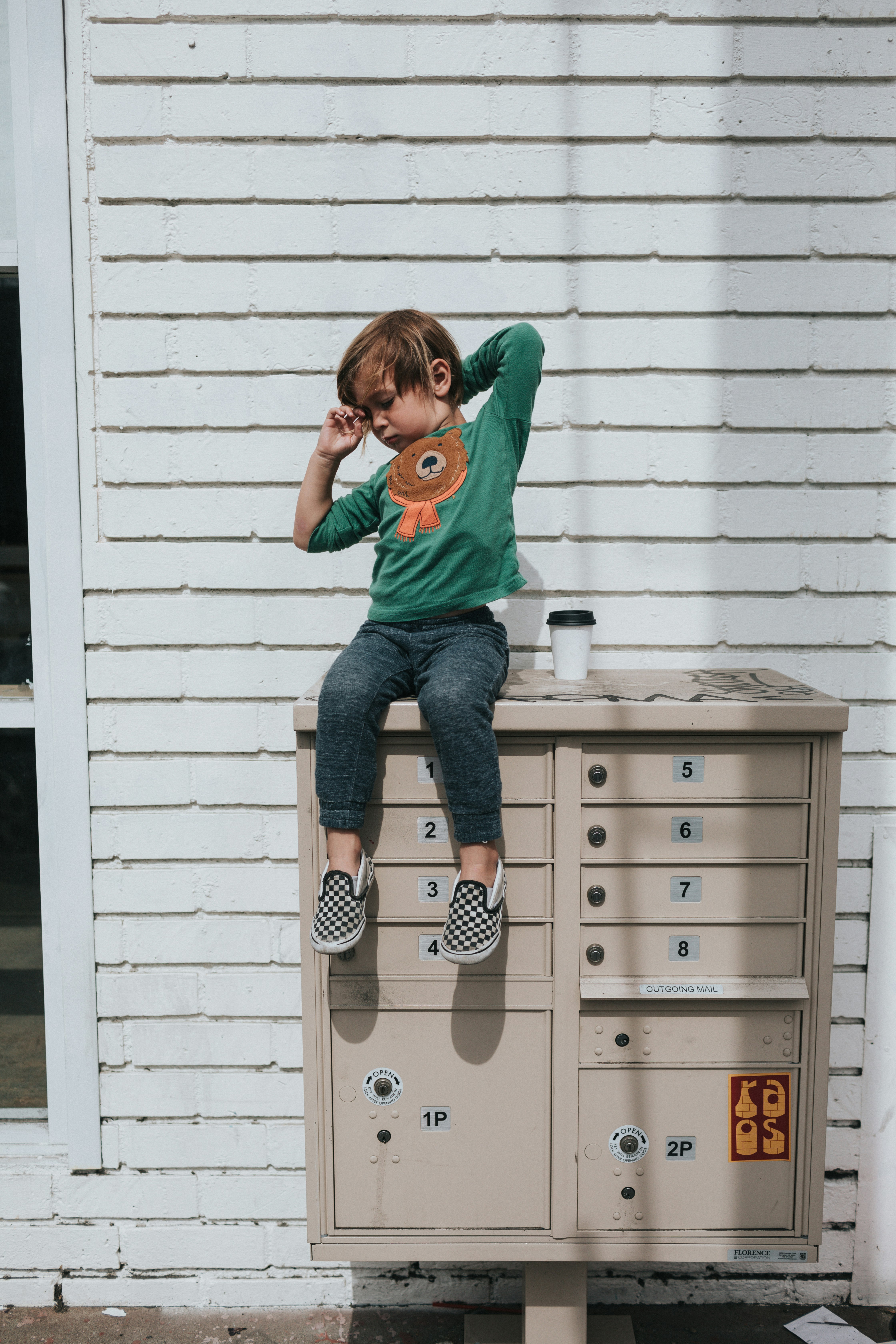 boy in green crew neck t-shirt and blue denim jeans sitting on white wooden drawer
